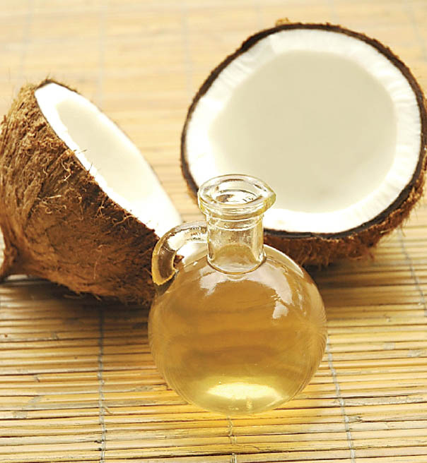 Óleo de coco Ocanda, dourado e translúcido, junto a um coco fresco
